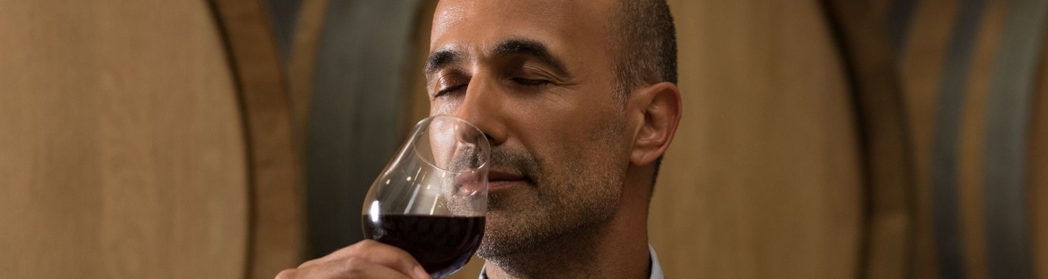 A picture of a winemaker in Stellenbosch smelling a glass of red wine before wine tasting  