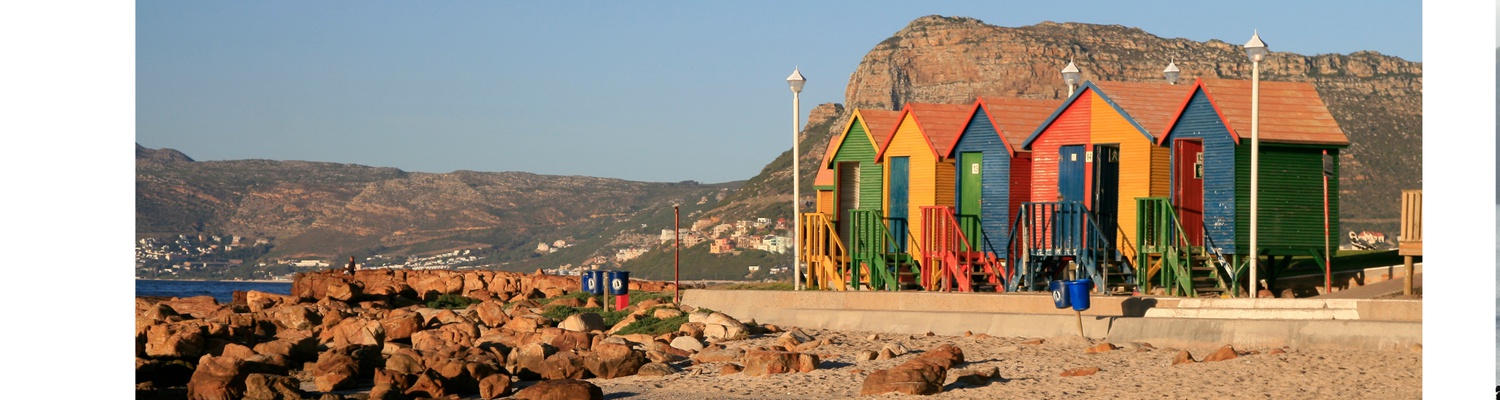 St James colourful beach changing huts with kalk bay harbour and mountains Cape Town Tours Into Tours 