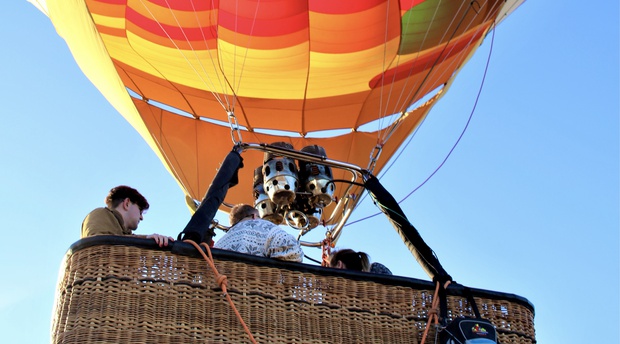 People that are in the basket of a Hot-Air-Balloon that is lifting off the ground in the Cape Winelands South Africa