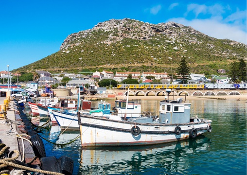 Kalk Bay scenic natural harbor of a suburban fishing village, featuring several piers & a 1913 stone marker